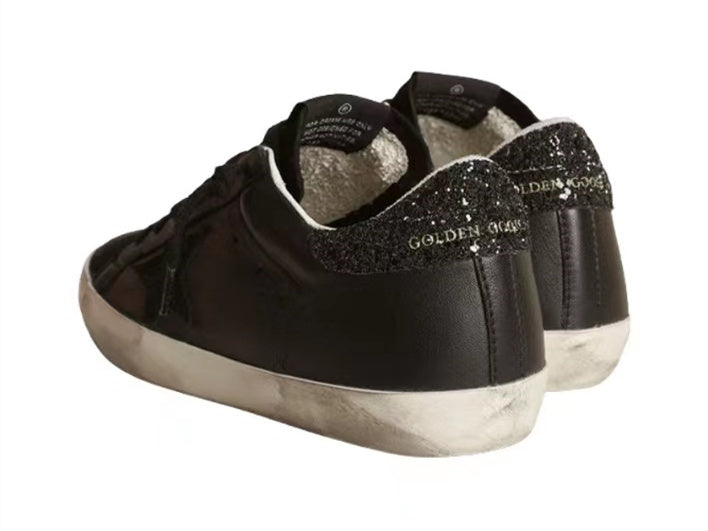 GOLDEN GOOSE حذاء سوبر ستار من جلد النابا الأسود مع نجمة سوداء وعروة كعب لامعة