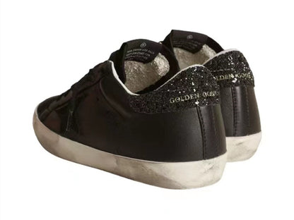 GOLDEN GOOSE حذاء سوبر ستار من جلد النابا الأسود مع نجمة سوداء وعروة كعب لامعة